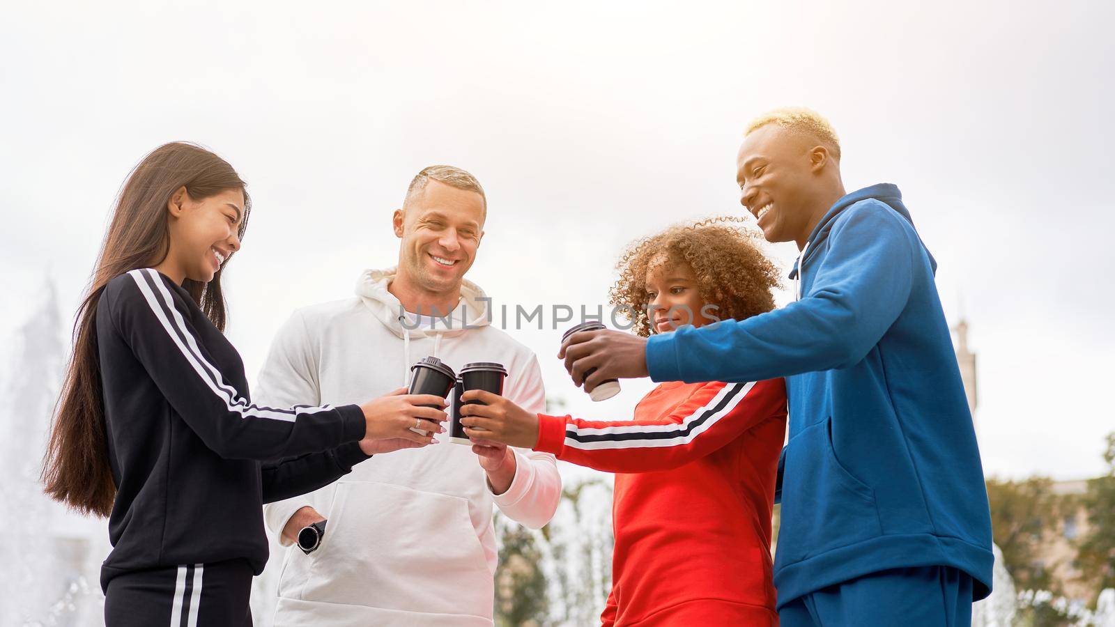 Multi-ethnic group teenage friends. African-american asian caucasian student spending time together Multiracial friendship Happy smiling People dressed colorful sportswear drink coffee outdoor