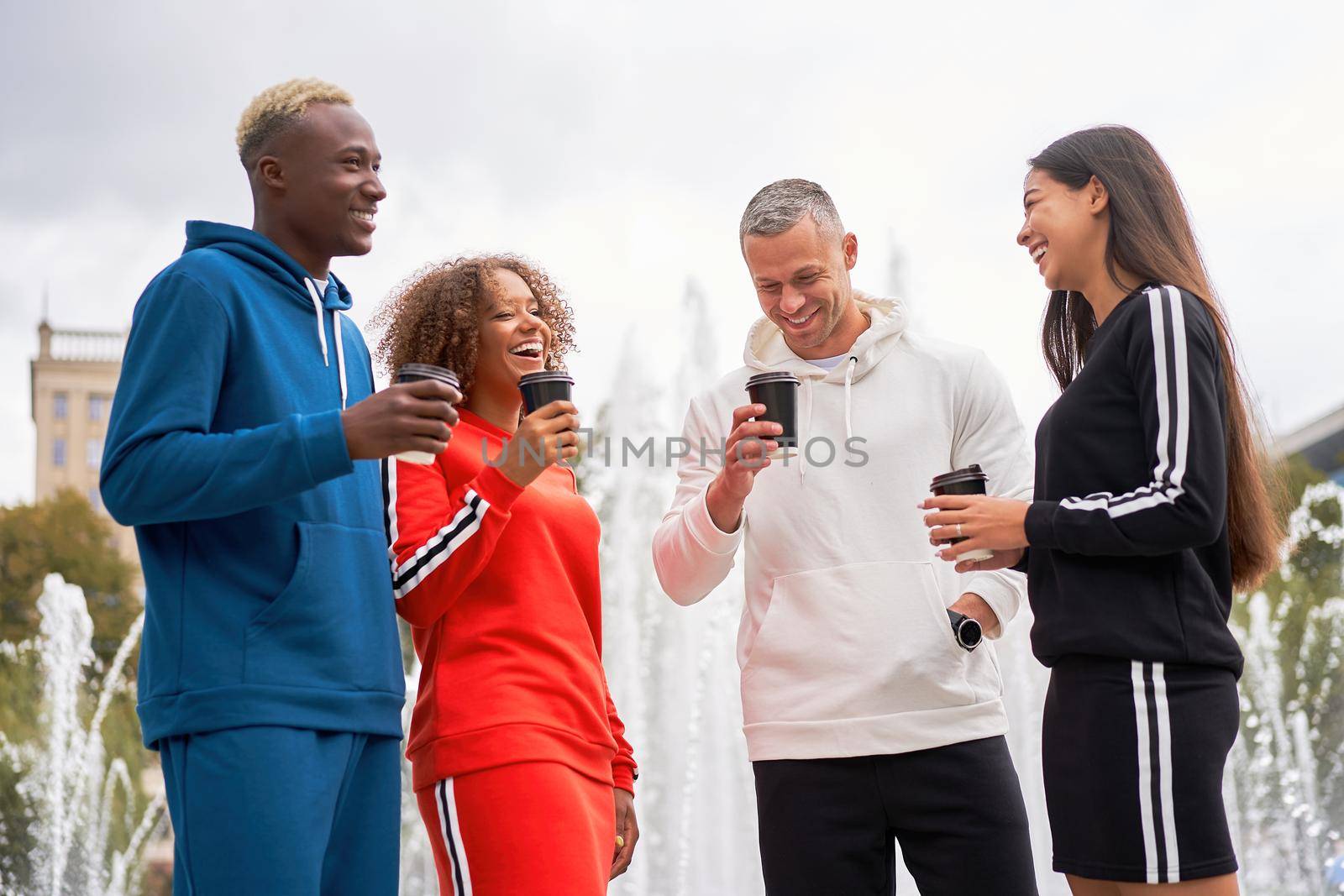 Multi-ethnic group teenage friends. African-american asian caucasian student spending time together Multiracial friendship Happy smiling People dressed colorful sportswear drink coffee outdoor