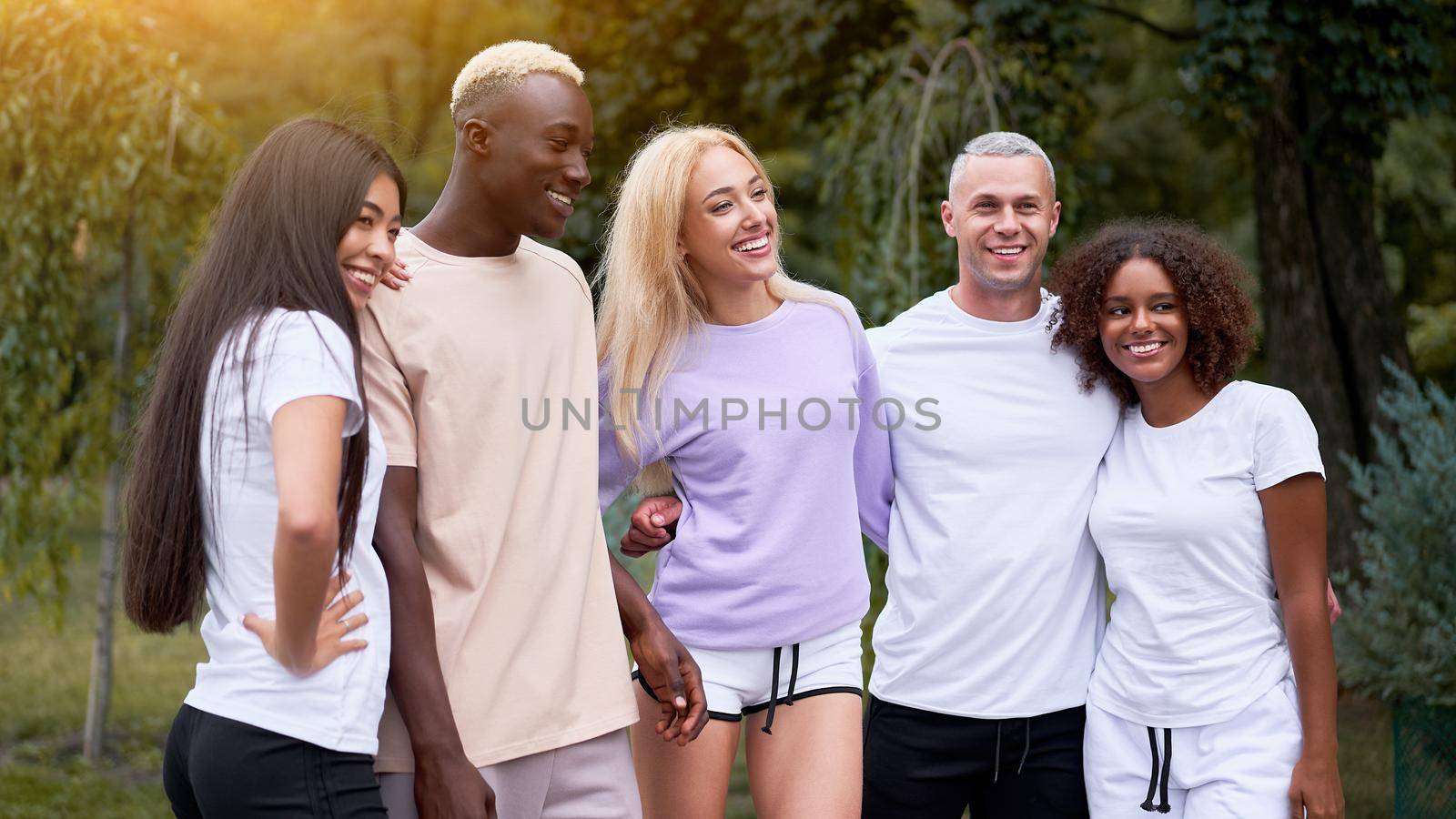 Multi-ethnic group teenage friends. African-american asian caucasian student spending time together Multiracial friendship Happy smiling People dressed black white sportswear meeting outdoor