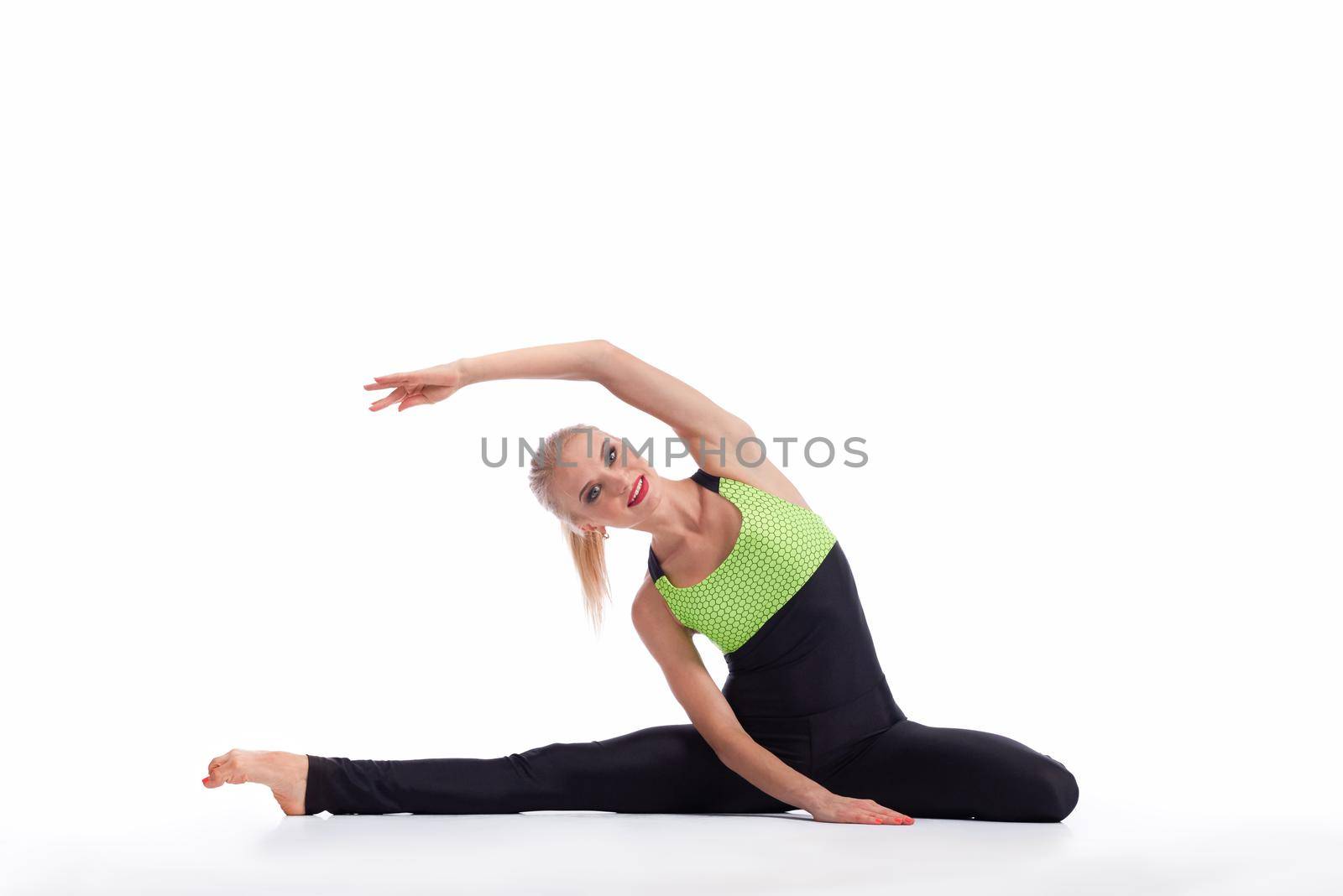 Important warm up. Horizontal studio portrait of a gorgeous happy female stretching doing sitting side bend smiling to the camera isolated copyspace
