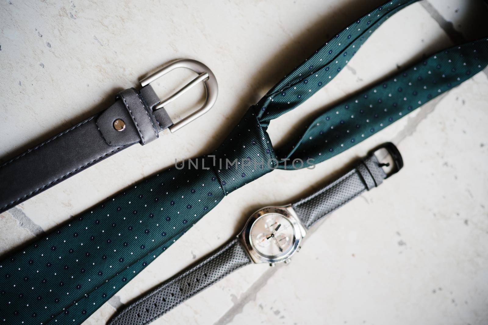 Men's belt, tie and watch on a light stone. High quality photo