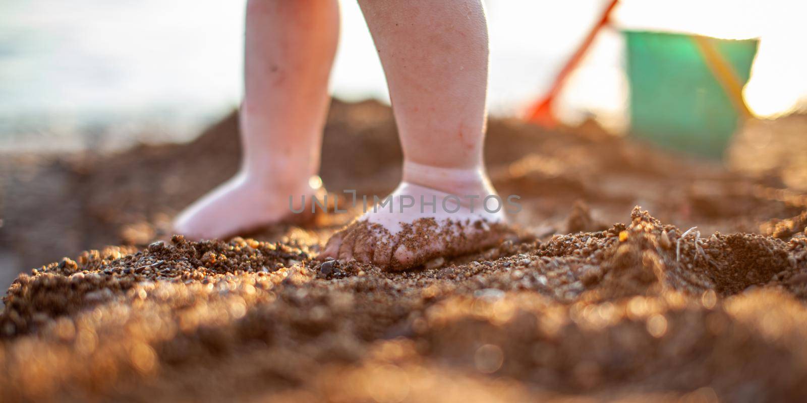Children's bare feet in summer on a golden sandy beach close-up. The concept of child safety. The concept of recreation with children.