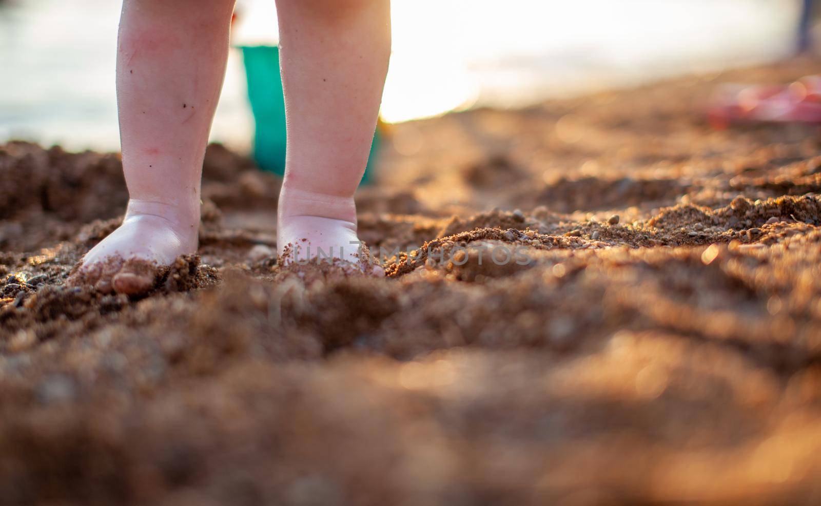 Children's bare feet in summer on a golden sandy beach close-up. The concept of child safety. The concept of recreation with children.