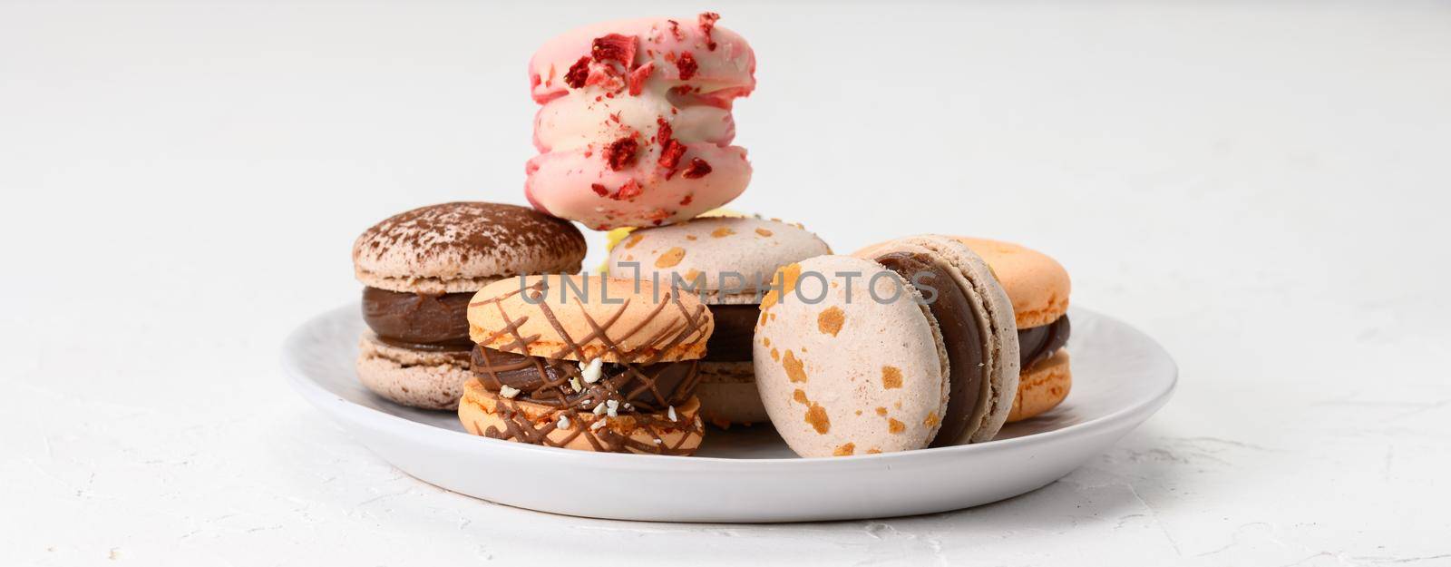 baked almond macarons on a white ceramic plate, white background