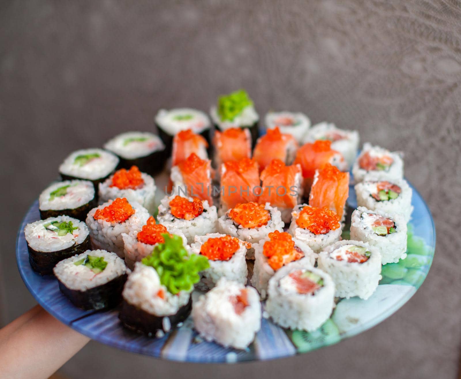 Making sushi and rolls at home. Sushi with seafood, salad and white rice. Food for family and friends. A set of different rolls and sushi on a tray.