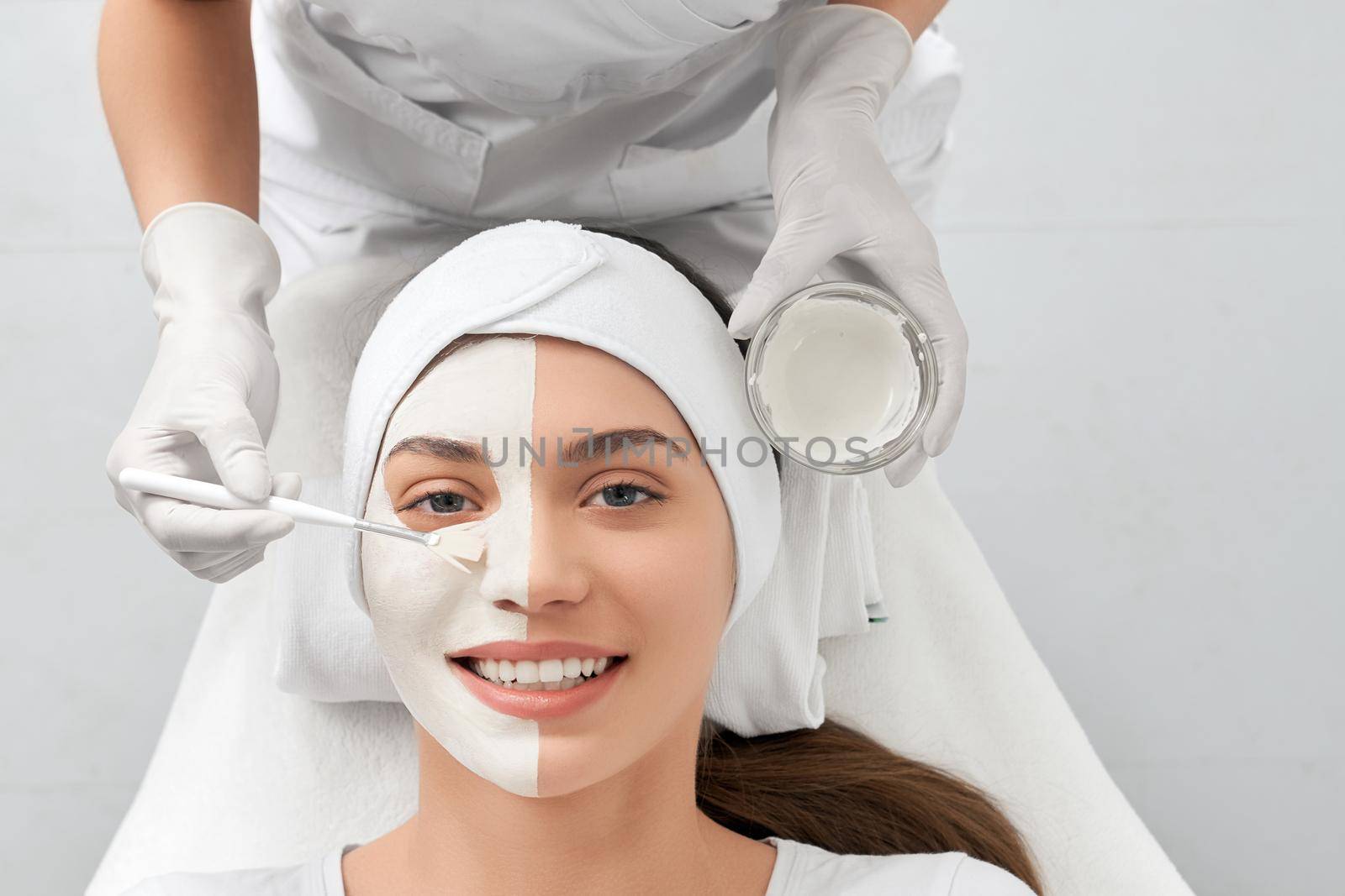 Top view portrait of attractive smiling young woman on cleaning face in beautician. Concept of special procedure for improvements and rejuvenation skin in professional beauty salon.