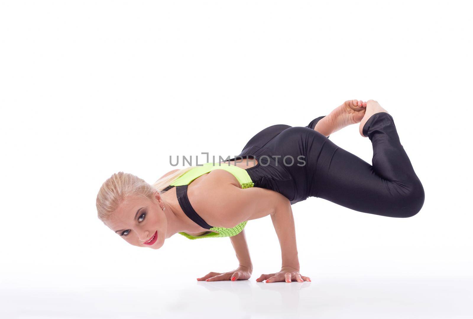Look easy, huh? Portrait of a beautiful female gymnast doing a handstand balancing gracefully on her arms smiling to the camera isolated