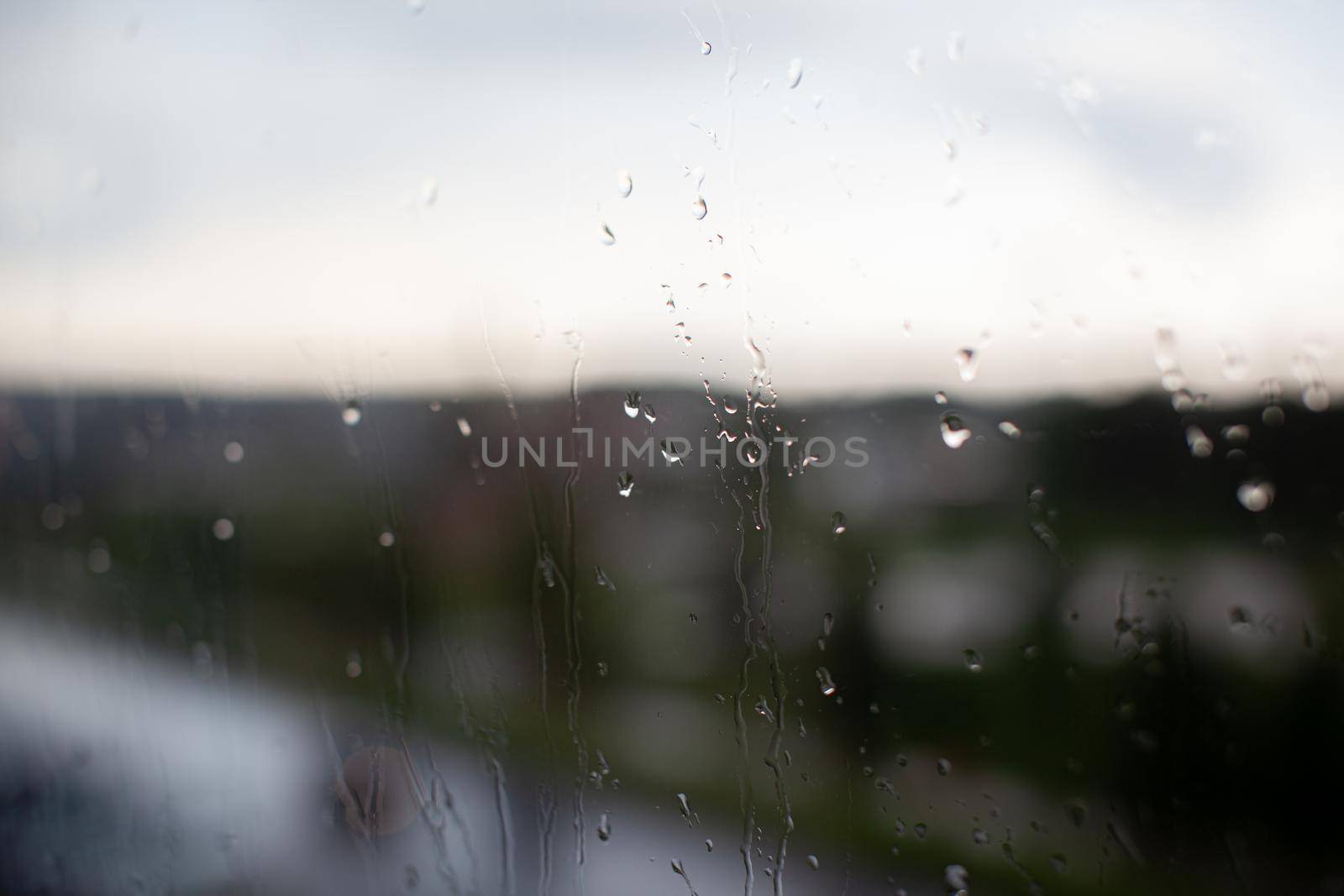 Rainy day through the window on sky and city buildings background by AnatoliiFoto