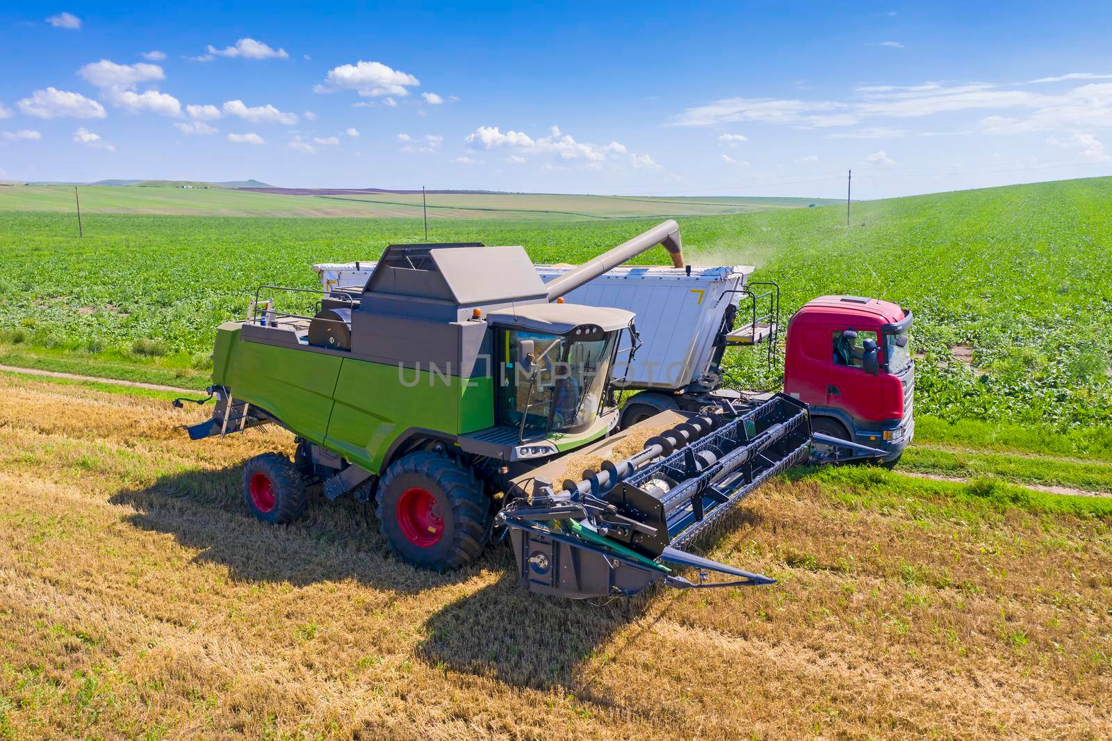 Combine harvester unloading cereal seed in a container truck on the field