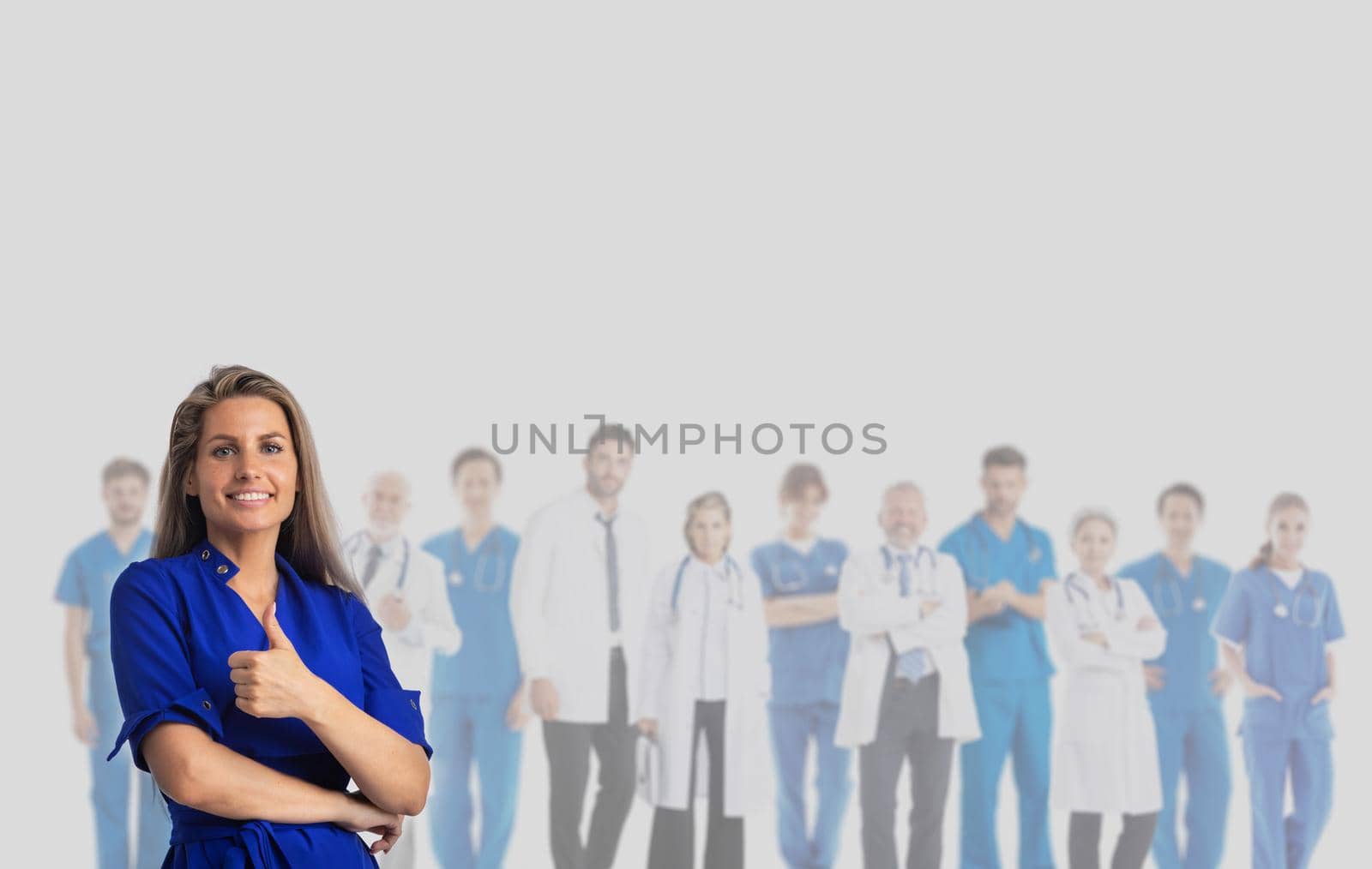 Happy female patient with thumb up and team of doctors on gray background with copy space for text