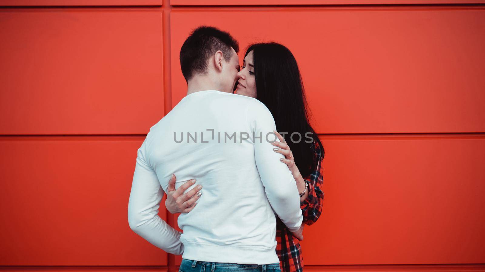 Couple kissing against isolated red wall in the city - red background, love concept