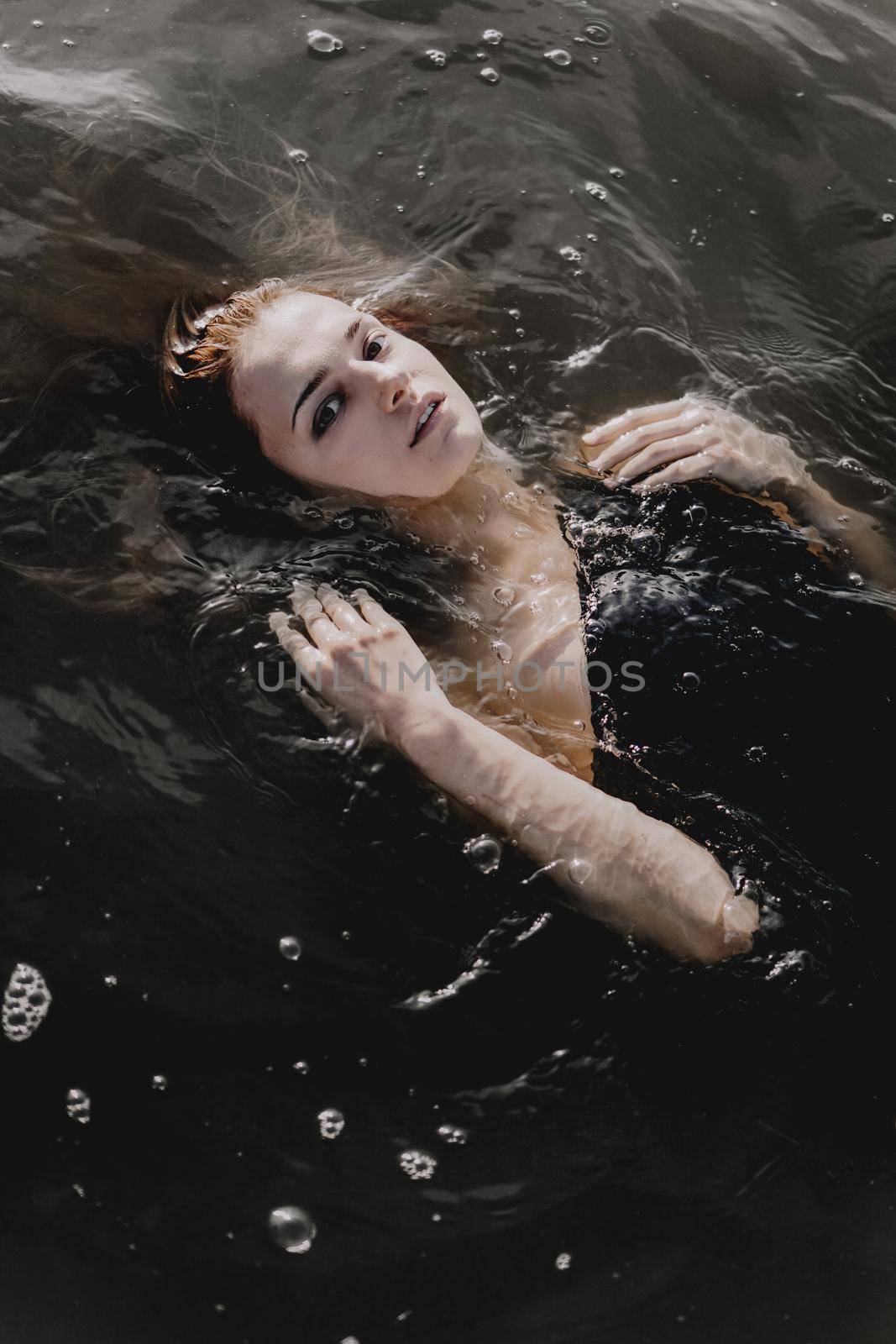 Young woman with raised arms in the water. Black water by natali_brill