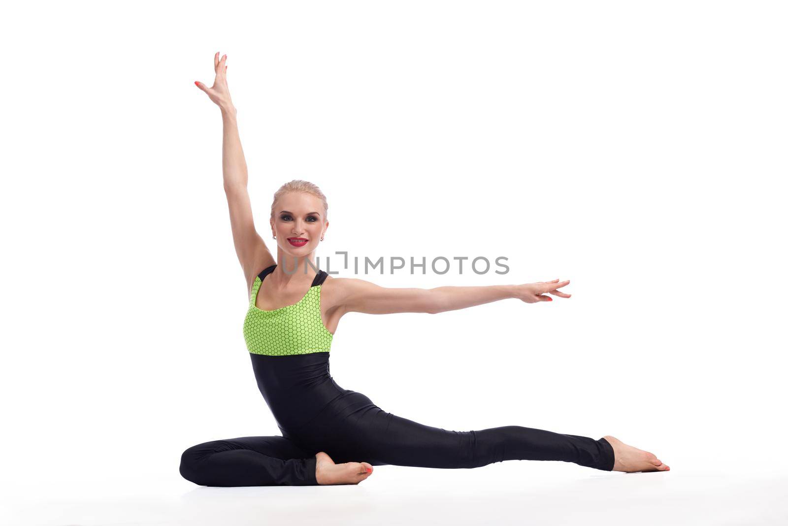 Flexible gymnast. Horizontal shot of a beautiful female gymnast posing gracefully after her performance sitting on the floor isolated copyspace