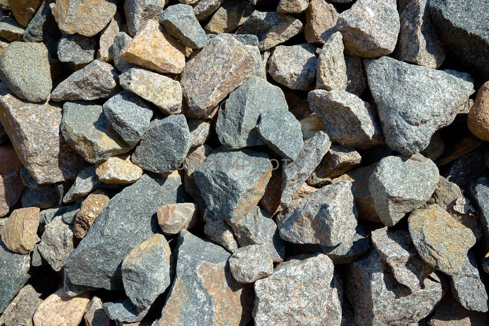 Gray texture of large pieces of stones crushed and broken into irregular shapes and sizes in a stone quarry.