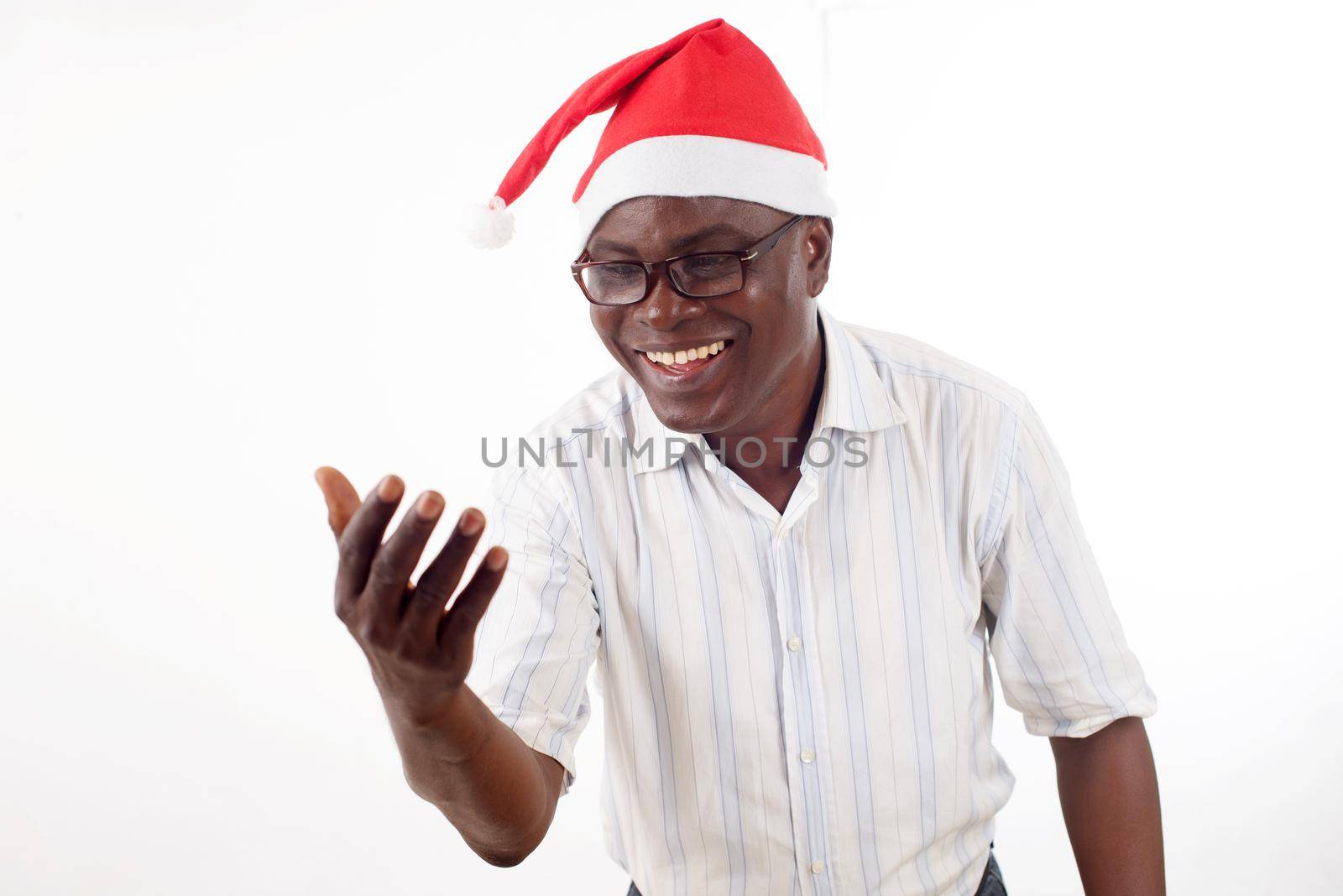 portrait of a happy man standing looking in his hand, with a Santa Claus hat isolated on a white background.
