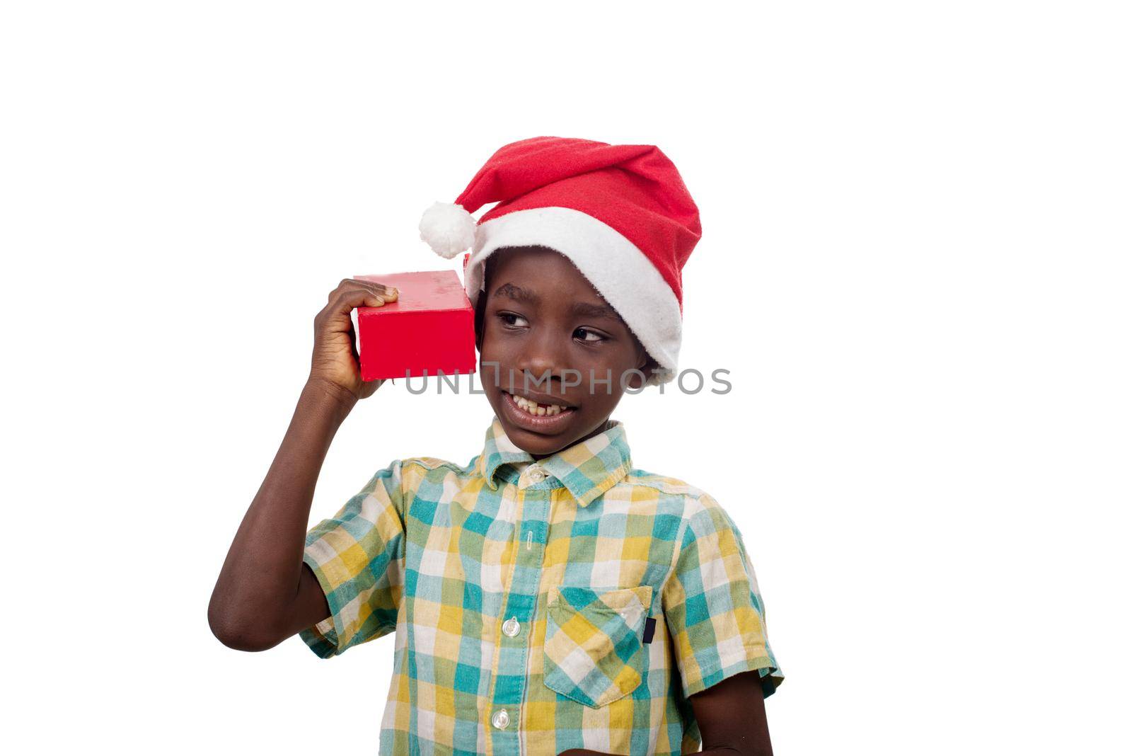 portrait of little boy in Santa Claus hat stirring box of his Christmas present.