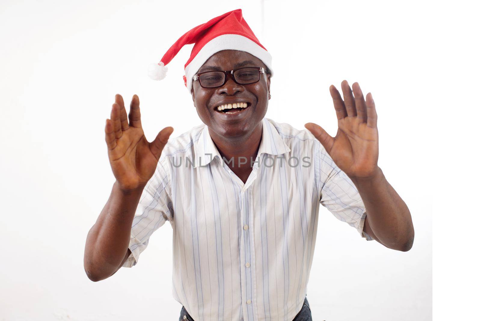 portrait of a happy man standing arms in front, wearing a Santa Claus hat isolated on a white background.
