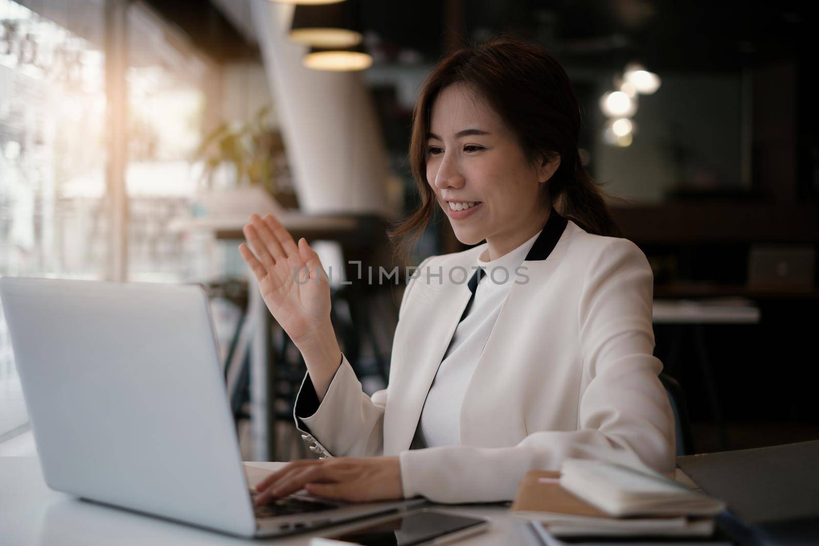 Joyful businesswoman sitting at desk looking at laptop screen talking with friend make informal video call.