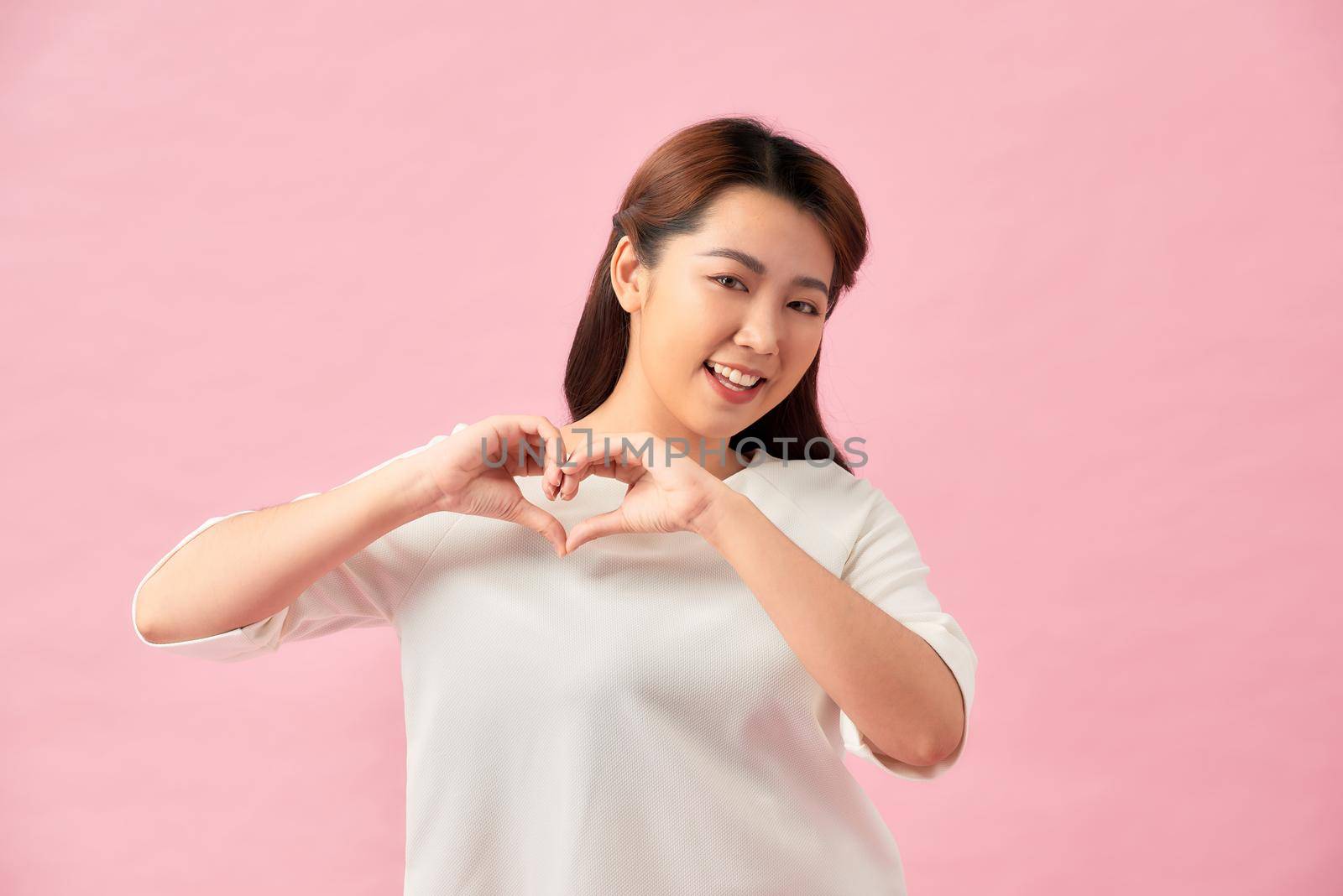 Young beautiful woman happy showing love with hands in heart shape