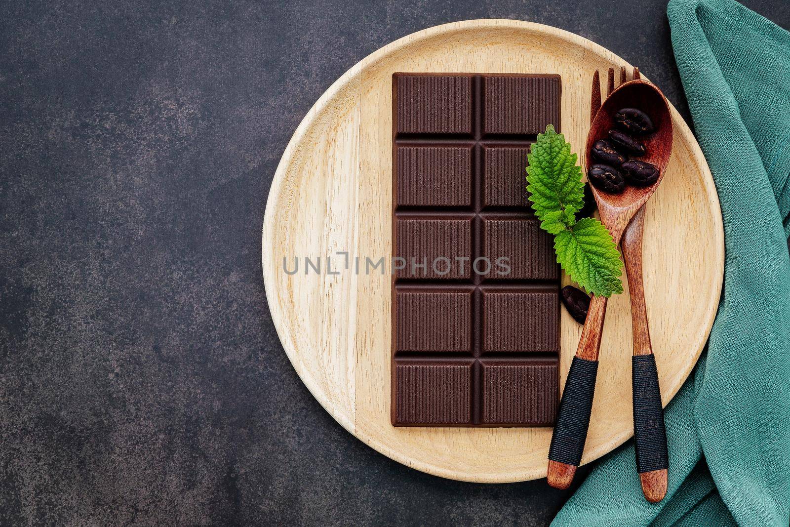 Food conceptual image with dark chocolate and fork on dark concrete background.