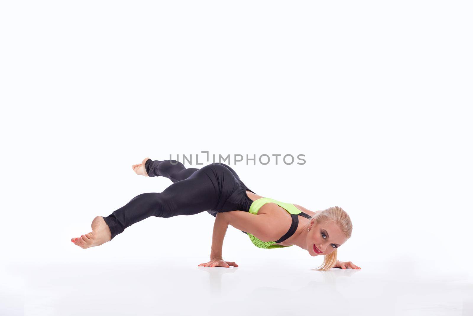 Balance and strength. Beautiful strong female gymnast performing a handstand working out smiling to the camera isolated on white copyspace