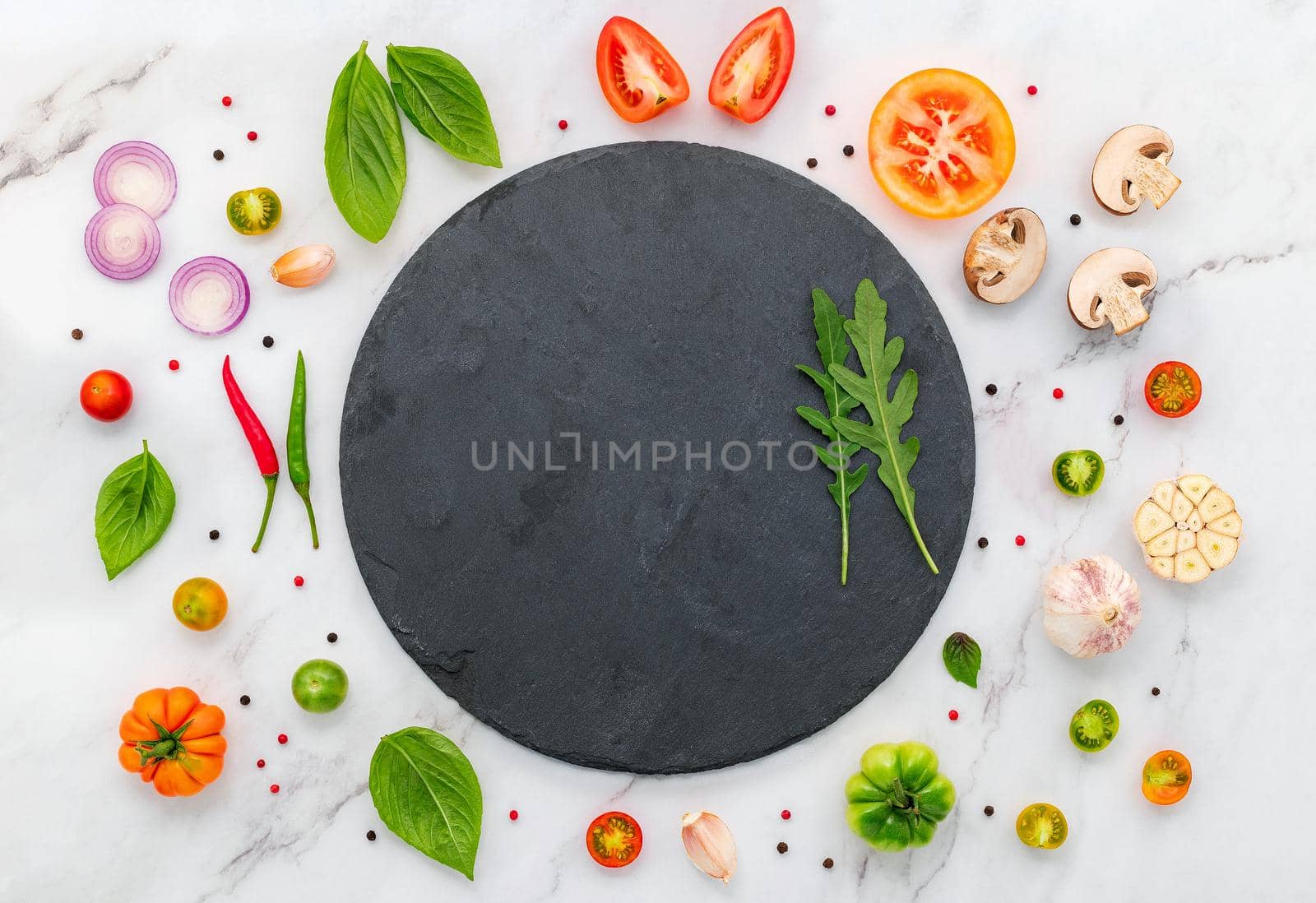 The ingredients for homemade pizza set up on white marble background.