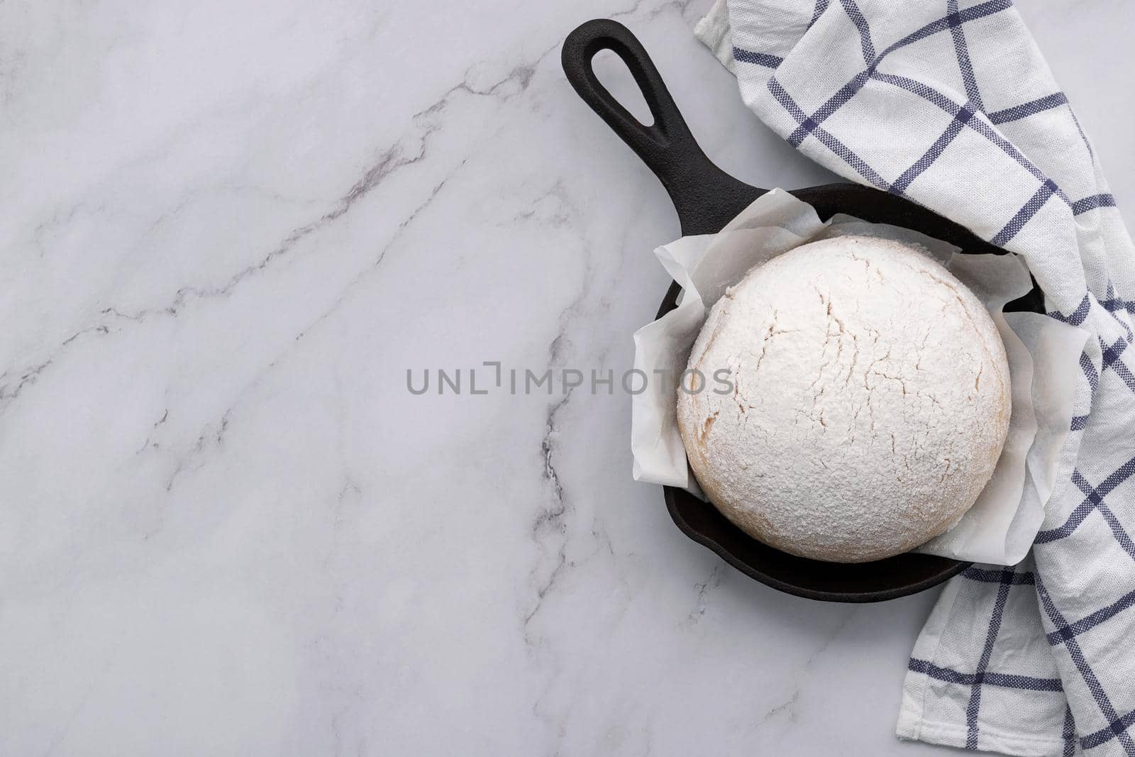 Fresh raw  homemade yeast dough resting in cast iron skillet on marble table flat lay.
 by kerdkanno