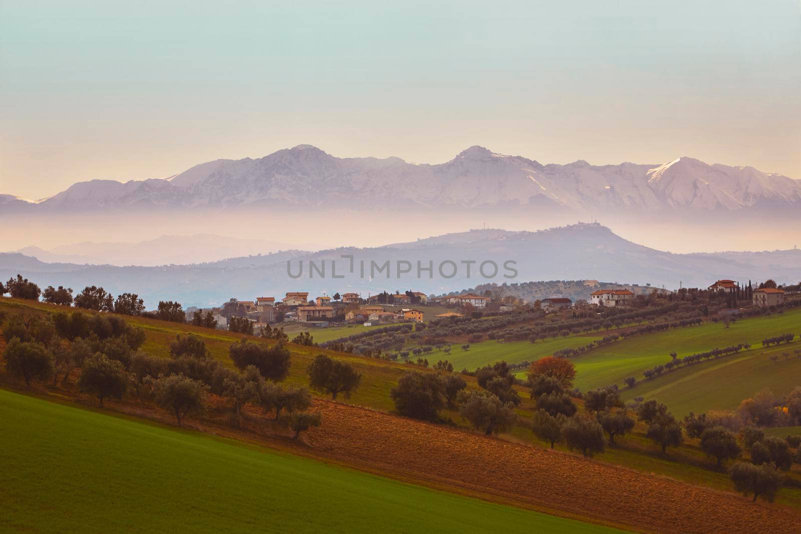 Panorama of the Italian countryside with misty and snowy mountains in distance