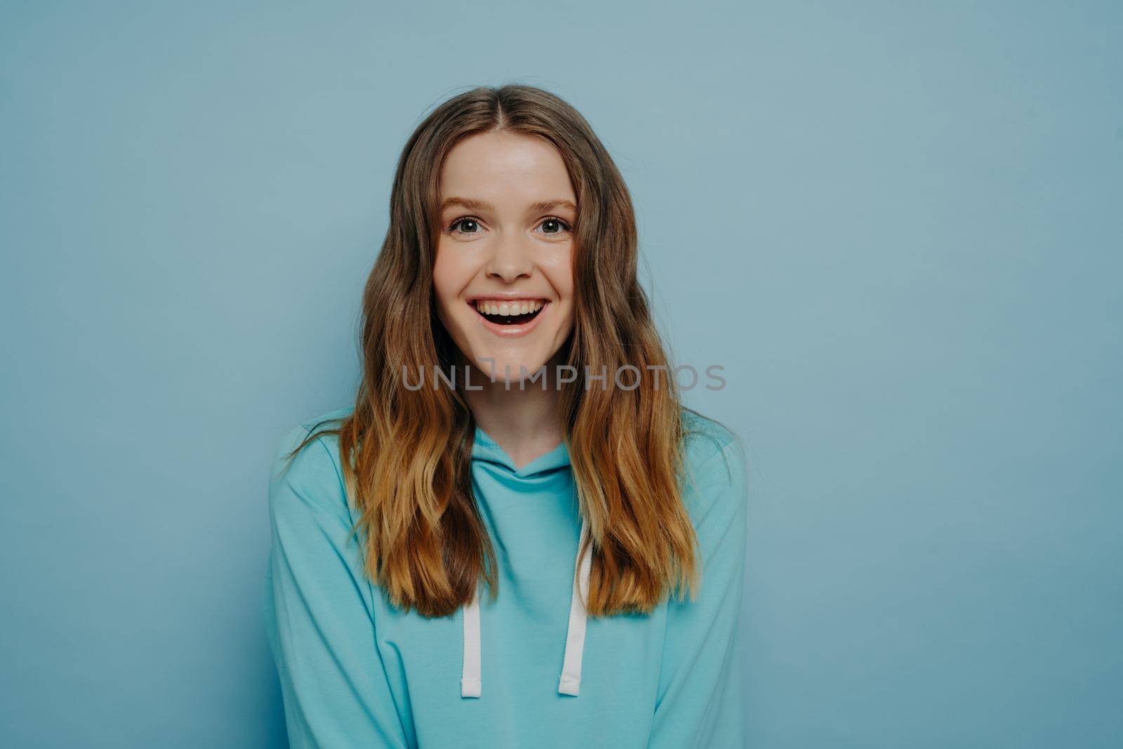 Laughing teenager wearing casual hoodie looking with positive expression at camera by vkstock