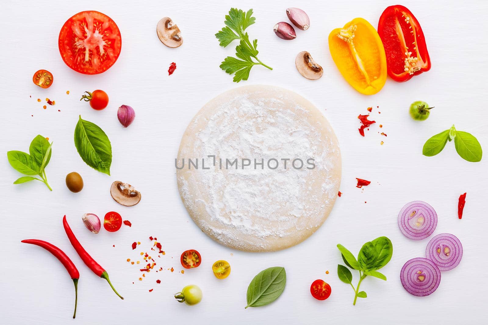 The ingredients for homemade pizza on white wooden background.