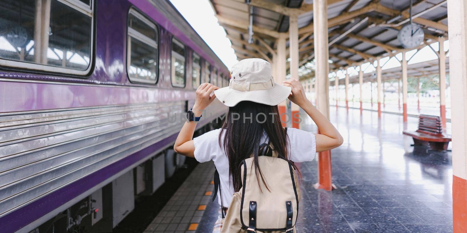 At the train station. Traveler woman tourist hand holding hat and backpack taking the train to travel. Active and travel lifestyle concept.