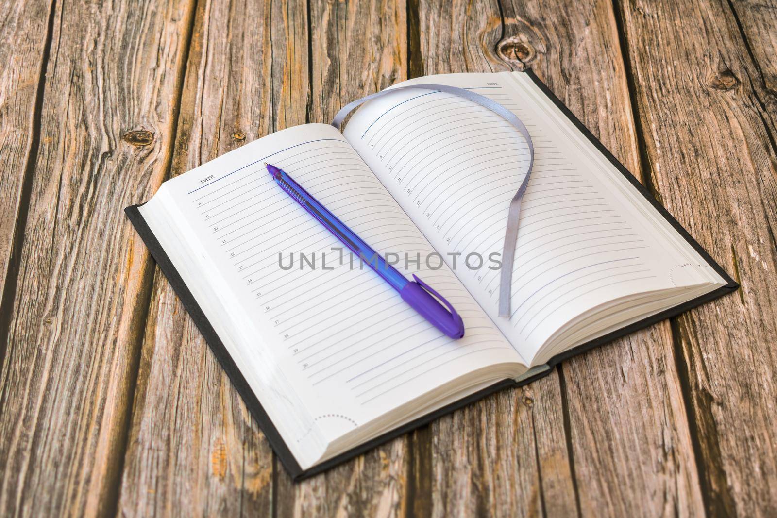 An open diary with blank pages on which a ballpoint pen rests, ready to record events or tasks