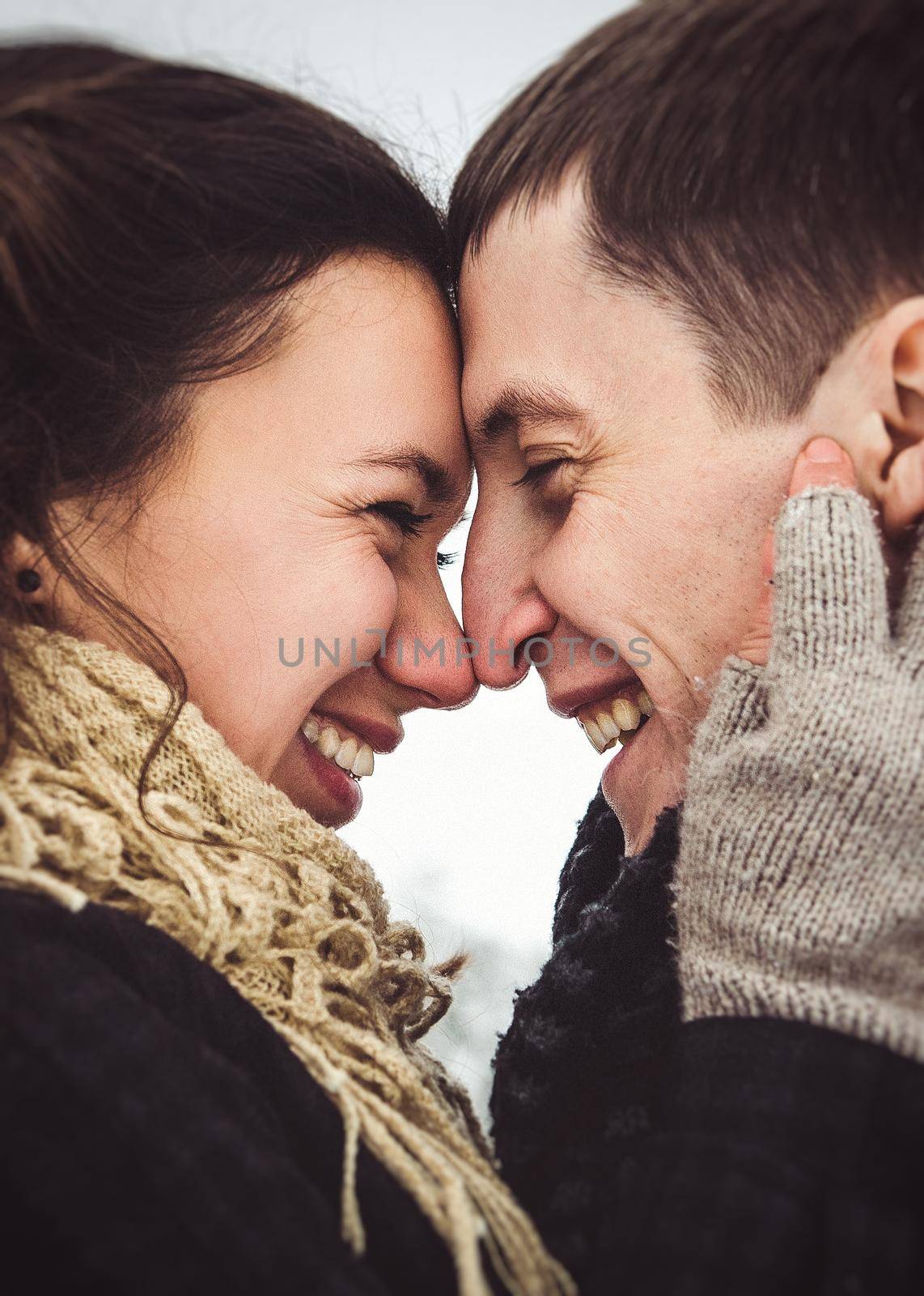 A guy and a girl in warm clothes and scarves on a walk in the snowy forest and in the field