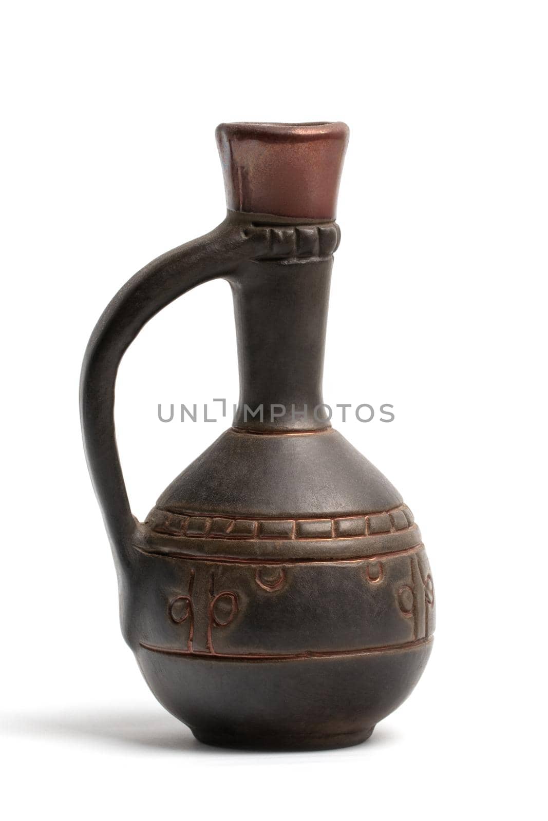 A small brown clay jug with patterns and a narrow high neck close-up view isolated on a white background.