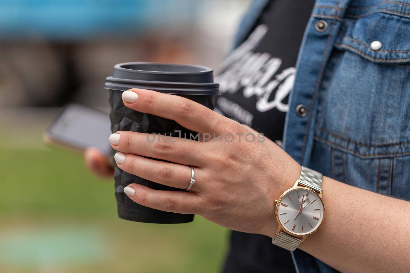 Close up of women's hands holding cell telephone and a cup of coffee by clusterx