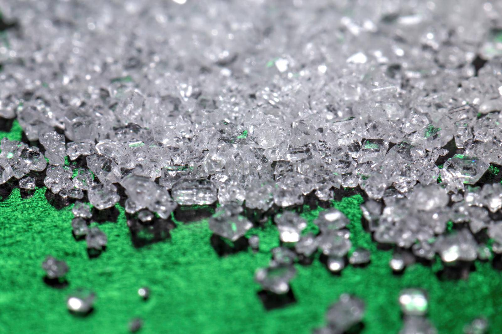 White sugar crystals on a dark green background, macro, close-up