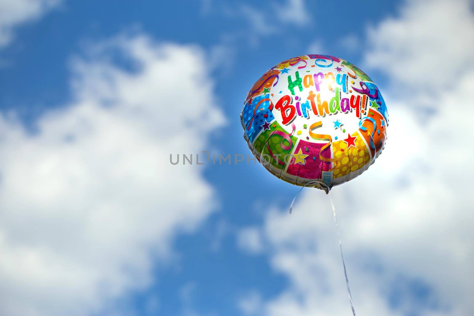 Colorful happy birthday balloon on a blue sky background by clusterx