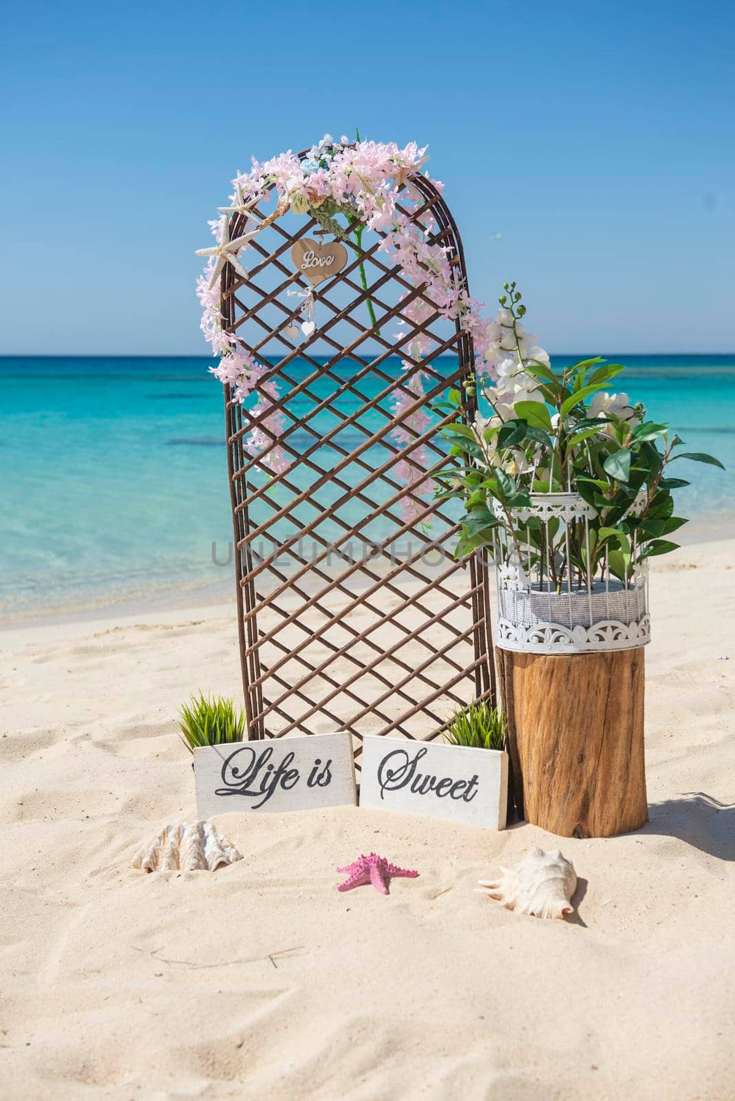 Closeup of wedding sign and decorations on tropical island sandy beach paradise with ocean in background