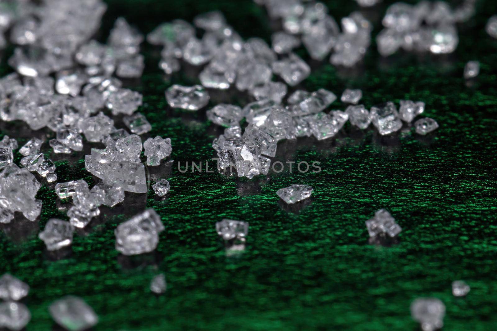 White sugar crystals on a dark green background, macro, close-up