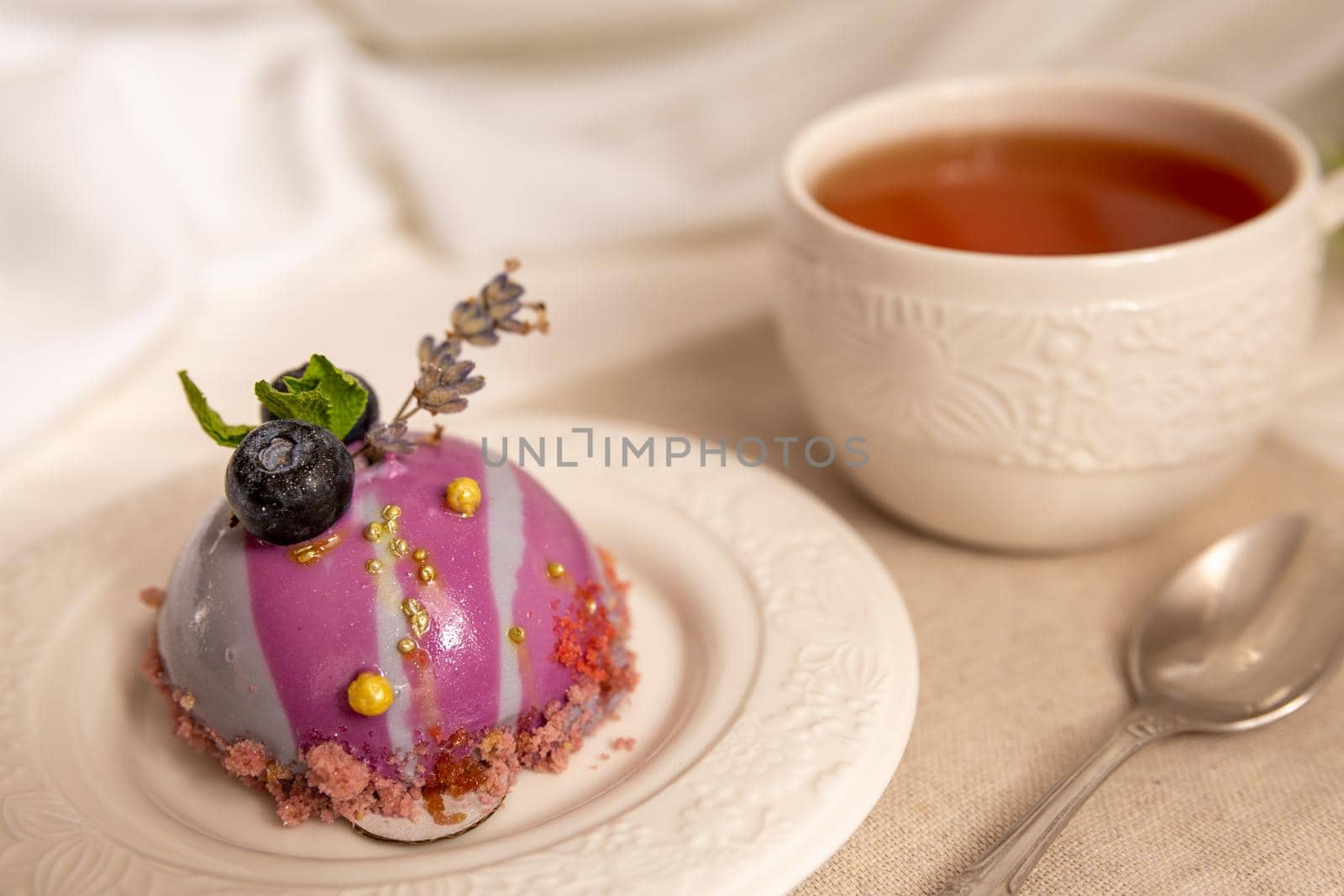 Still life with a cup of tea and sweet cake on white wooden table. Breakfast in the morning sun