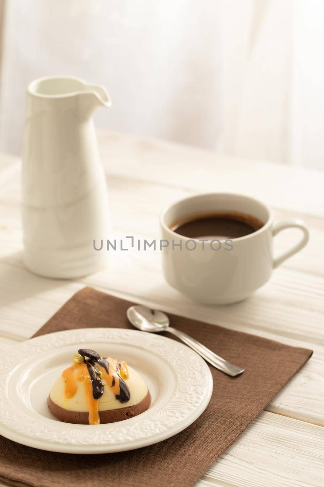 Still life with a cup of coffee and sweet cake on white wooden table. Breakfast in the morning sun