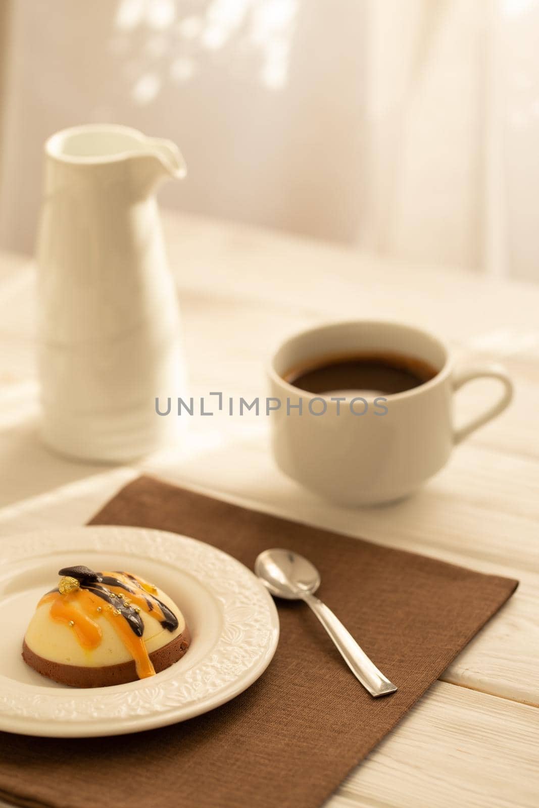 Still life with a cup of coffee and sweet cake on white wooden table. Breakfast in the morning sun