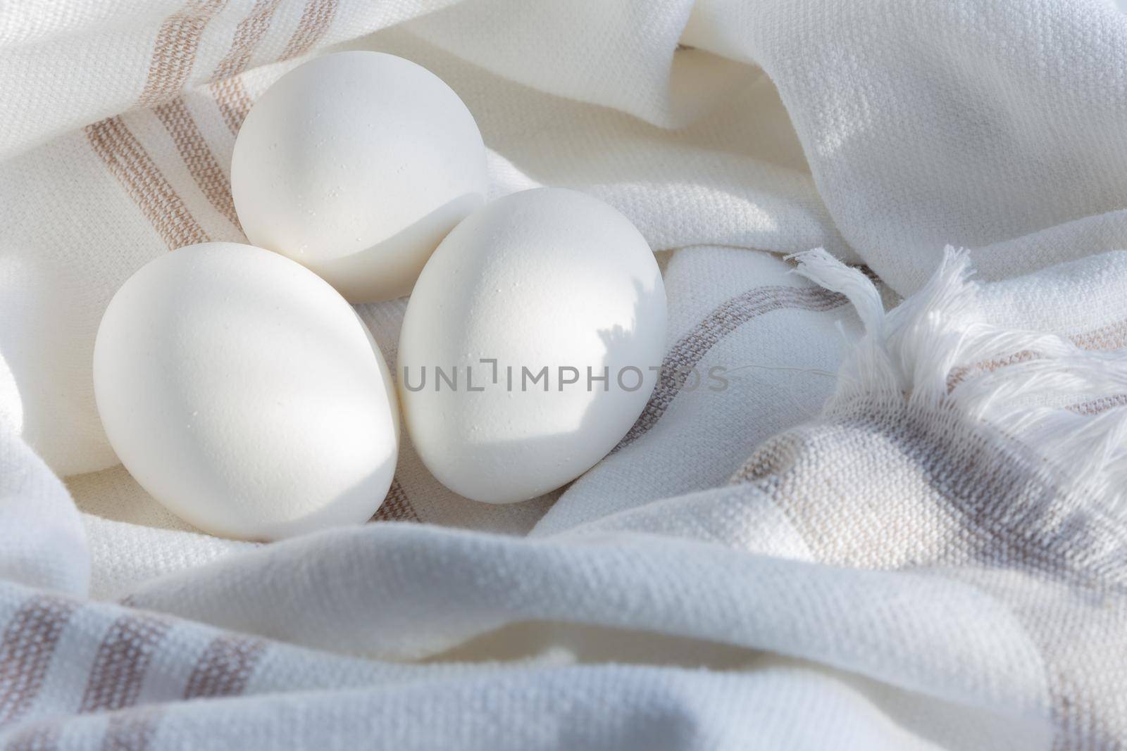 Fresh chicken eggs on a linen towel under a soft sunlight. Scandinavian rustic style.