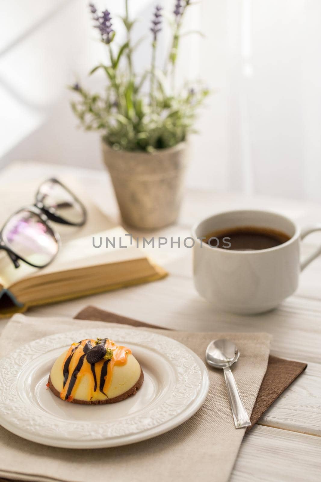 Still life with coffee, cake and a bouquet of lavender on white wooden table. Breakfast in the morning sun