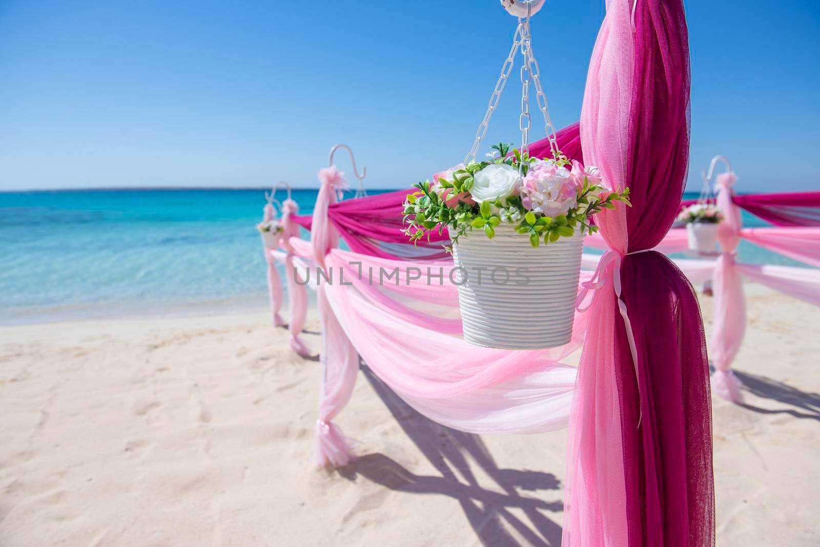 Setup of wedding day marriage aisle with drapes and arch on sandy tropical beach paradise to open ocean background 