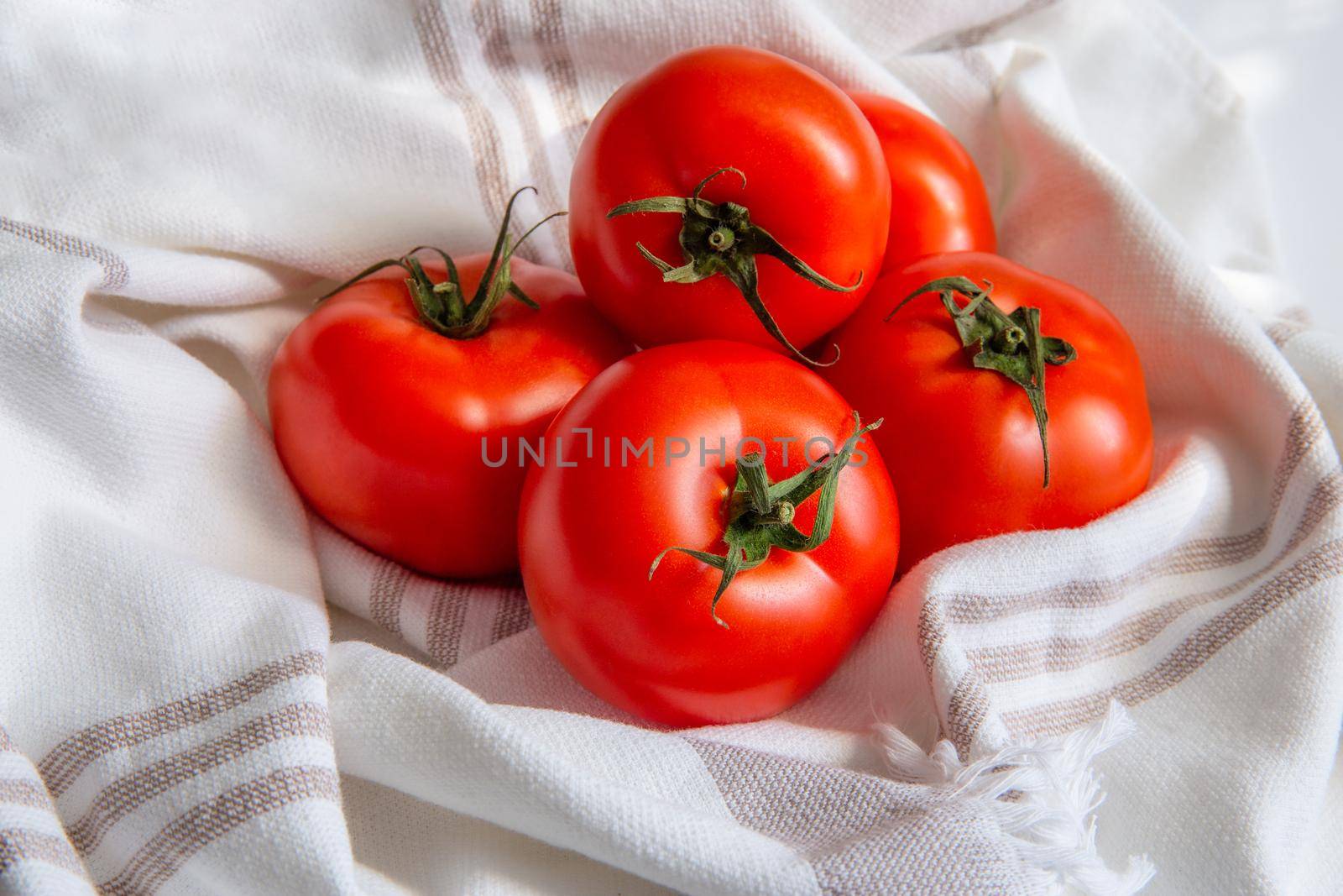 Ripe fresh red tomatoes in a linen towel under soft sunlight