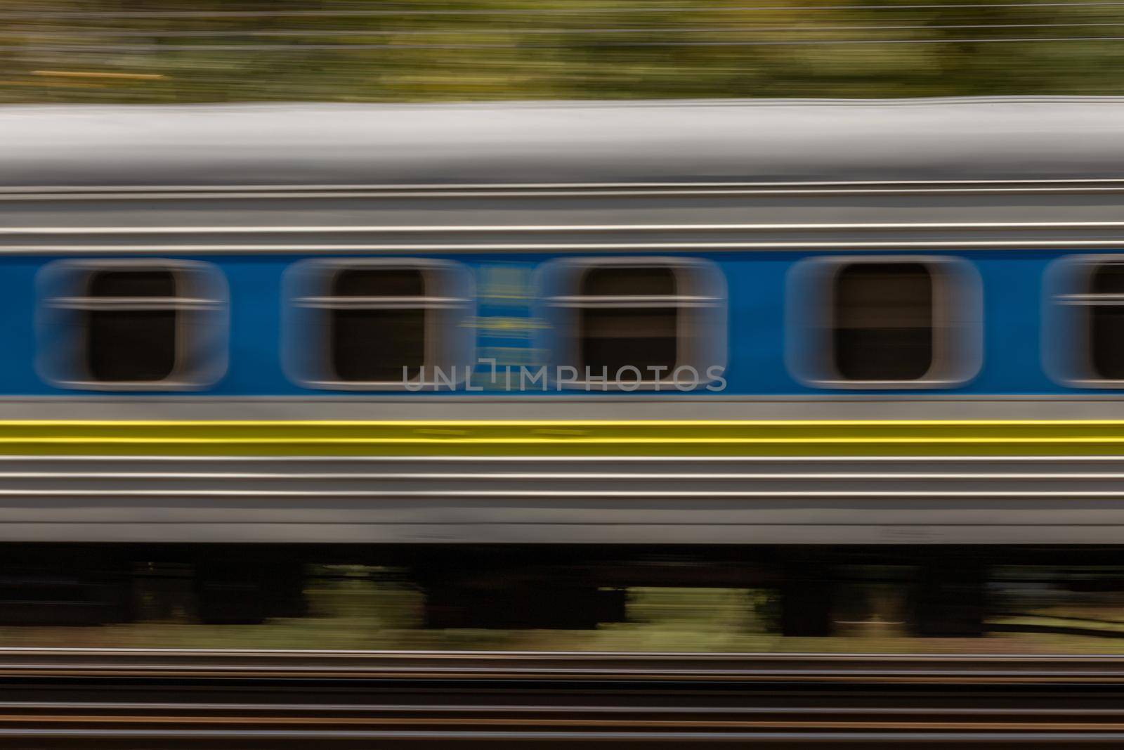 Railroad train high dynamic motion blur, abstract blurred background with green trees, side view