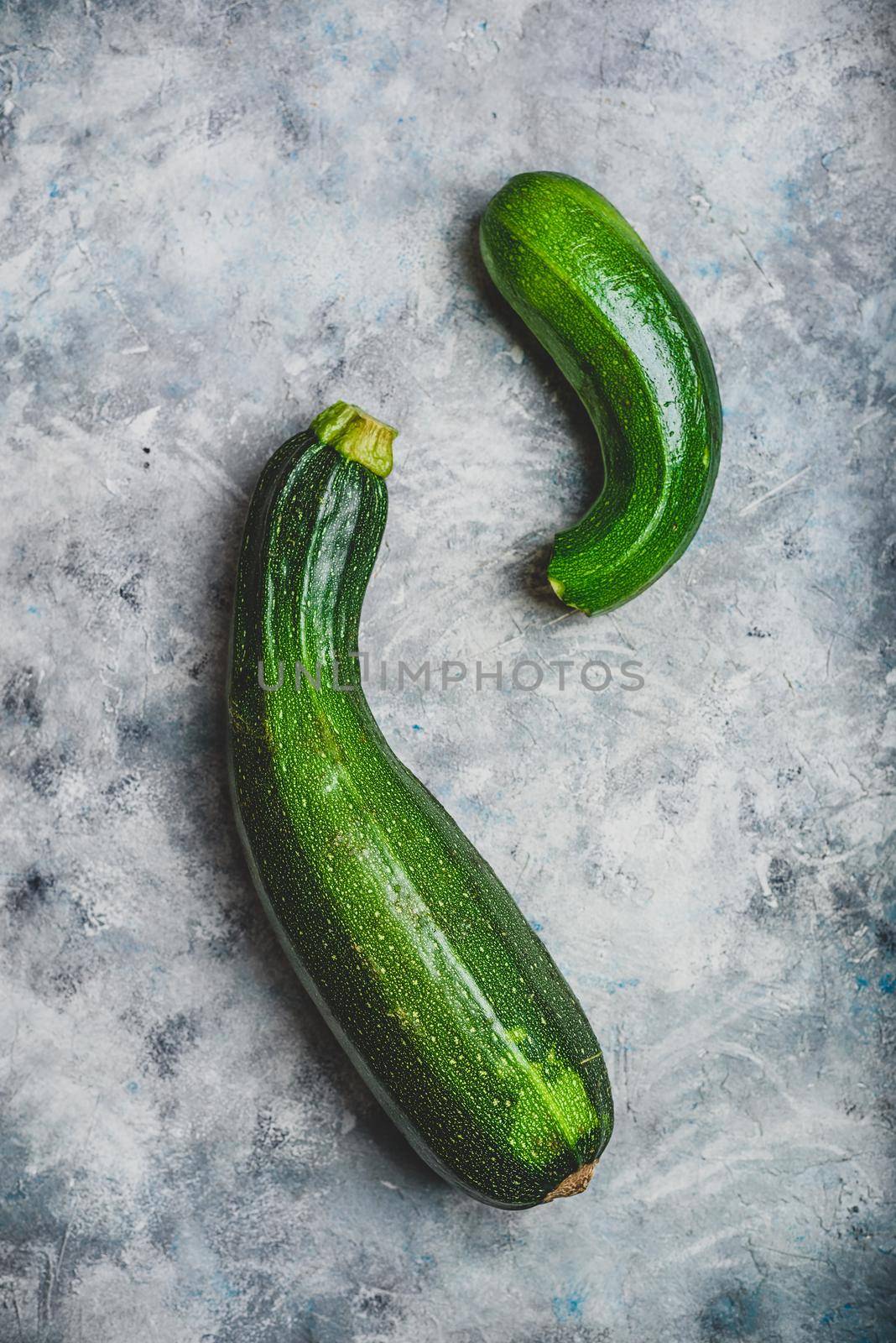 Two fresh organic zucchini on a concrete background. View from above