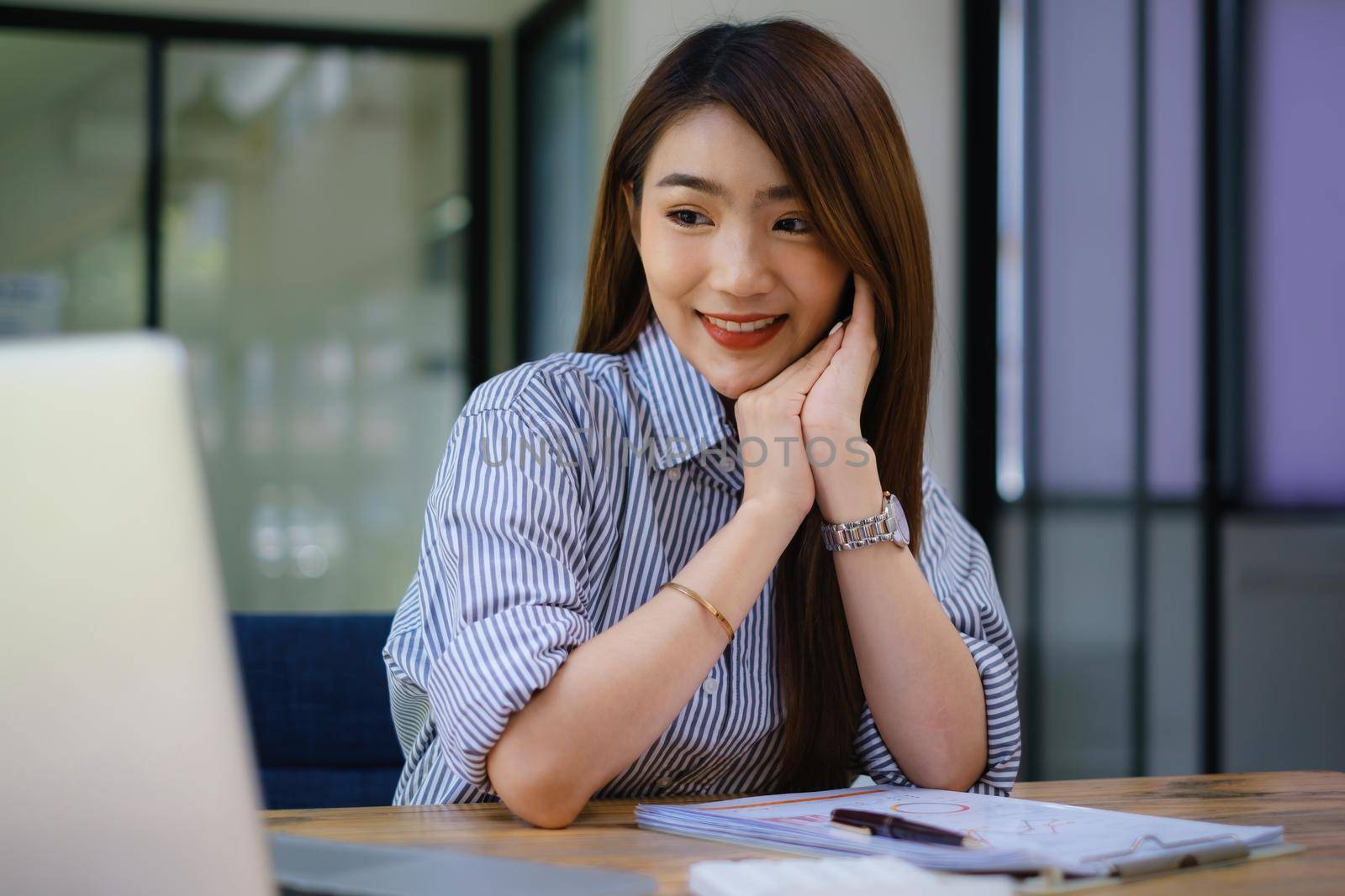 Joyful businesswoman sitting at desk looking at laptop screen talking with friend make informal video call