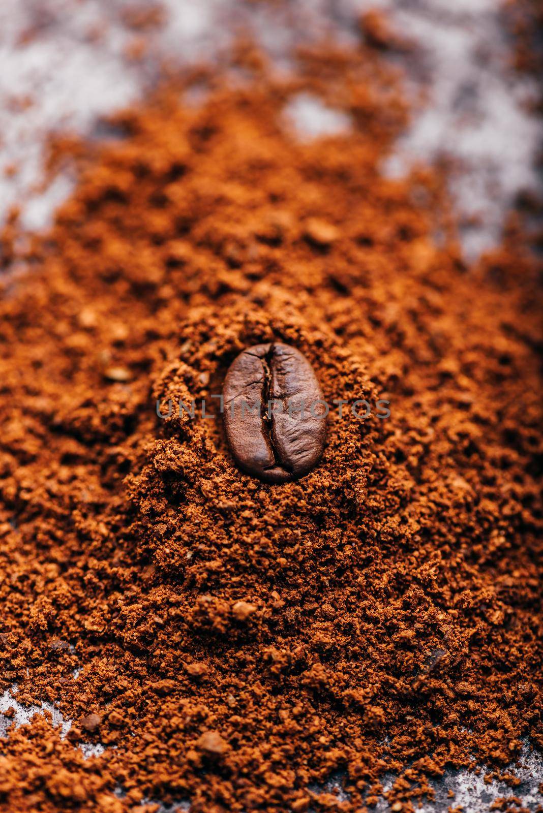 Fresh roasted coffee bean lays on heap of grinded coffee